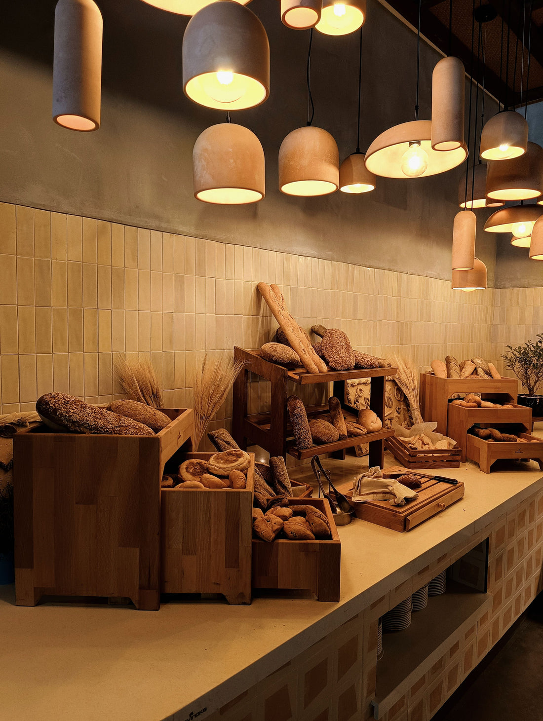 Warm artisan bakery display with rustic loaves and bread under pendant lights